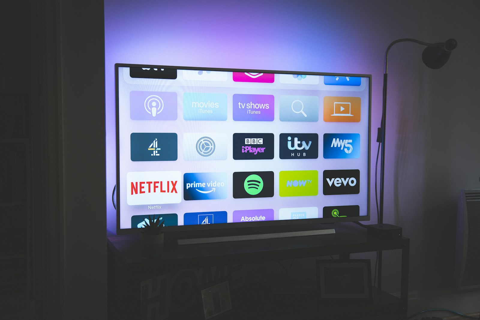 A television in a living room with a sofa and a floor lamp nearby